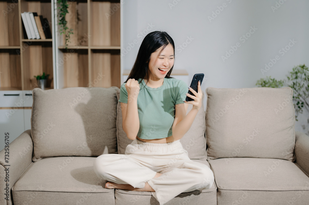 Young asian woman using smartphone and tablet while seated on couch at home. Young asian woman using smartphone and tablet while seated on couch at home.
