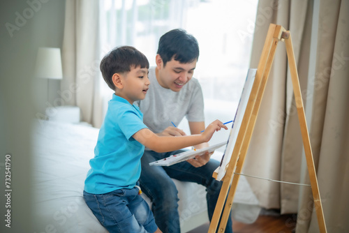 Young Asian Child and dad painting together on canvas and stand with smile of fun and happiness at home, relationship, activity with father and boy.