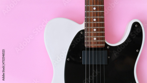 Black and white electric guitar on a pink background. Top view.