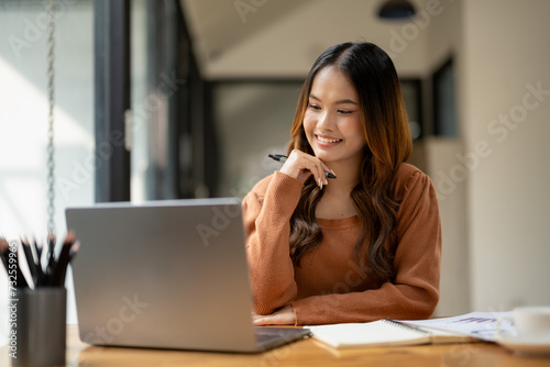 Wallpaper Mural Cheerful young woman in casual attire focusing on a laptop screen, working from a modern office. Torontodigital.ca