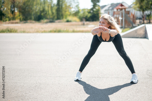 Sexy sporty woman stretching and warming up legs for running urban fitness workout. Sport and healthy lifestyle concept. Female athlete exercising outside