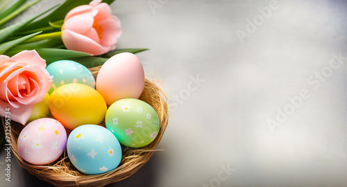 Multicolored painted eggs with delicate spring flowers in the nest against a light gray stone background. The concept of the Spring and Easter holiday with a copy space