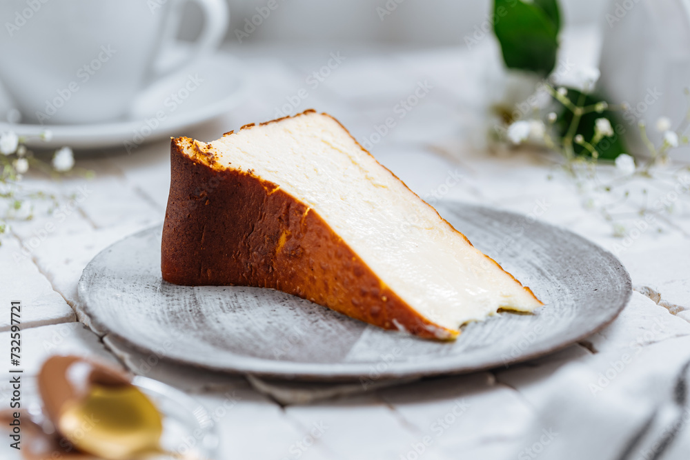Fototapeta premium Popular Spanish dessert called San Sebastian cheesecake. It also known as burnt cheesecake. One piece of this dessert on white background.