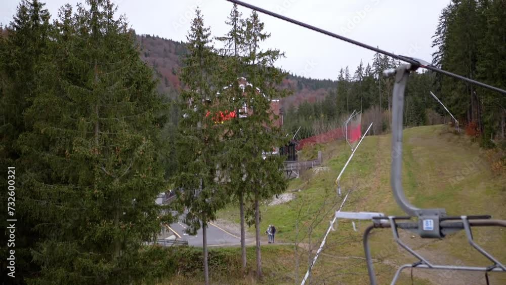 Empty Ski Lifts Move Up near Green Pine Trees against the Backdrop of Mountains. Riding a ski lift with a view of autumn Carpathian mountains, and tall spruce trees. Holidays at a resort in Bukovel. Empty Ski Lifts Move Up near Green Pine Trees against the Backdrop of Mountains. Riding a ski lift with a view of autumn Carpathian mountains, and tall spruce trees. Holidays at a resort in Bukovel.