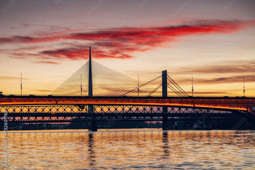 Obraz premium magnificent sunset over the Sava River in Belgrade, Serbia, illuminating Bridge and surrounding urban landscape with a golden glow.