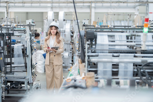 The owner of the industrial factory is a female engineer. Doing business exporting plastics and steel with overseas companies. Wear a suit, have a laptop, a radio, and have working machinery.