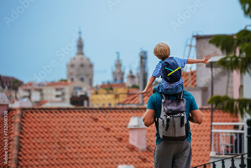 Father and son on his shoulders with backpack look at Lisbon