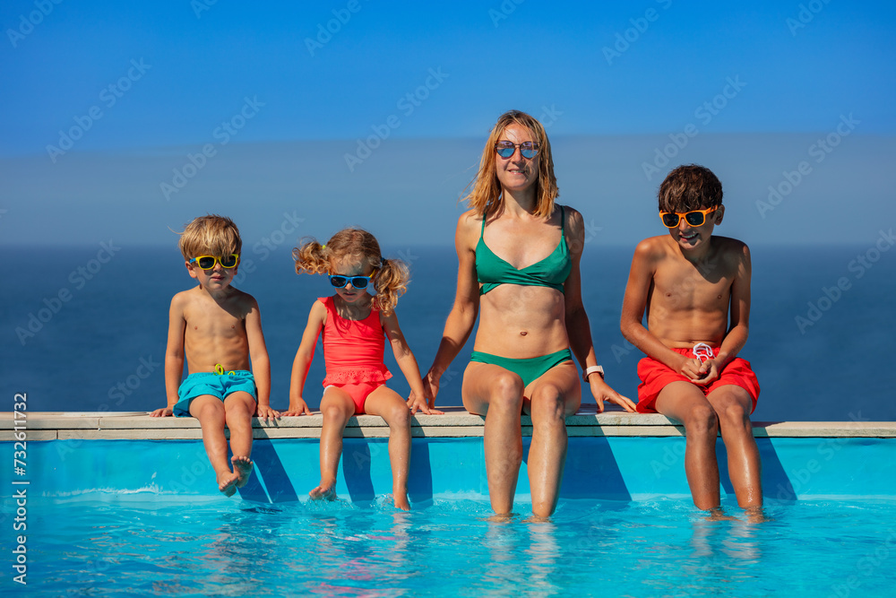 Woman and kids dangle their feet in the waters of resort pool Woman and kids dangle their feet in the waters of resort pool