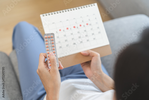 Tablou pe pânză Contraception, menstruation and pregnancy concept, birth control pills asian young woman holding hormonal oral contraceptive pills with calendar, menstrual cycle