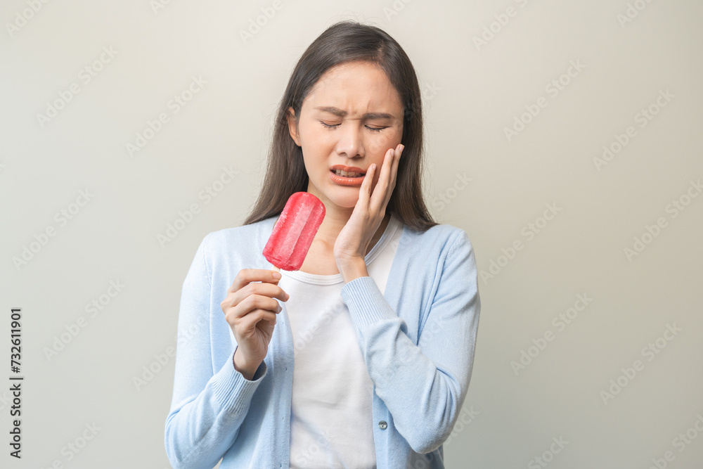 Face expression suffering from sensitive teeth and cold, asian young woman, girl hand touching cheek, hurt or pain eating ice cream. Toothache molar tooth, dental problem isolated on white background. Face expression suffering from sensitive teeth and cold, asian young woman, girl hand touching cheek, hurt or pain eating ice cream. Toothache molar tooth, dental problem isolated on white background.