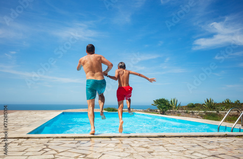Joyful dynamic pool jump of father and son by the sea view