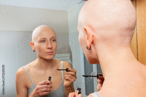 Young girl with cancer do mascara routine at bathroom mirror