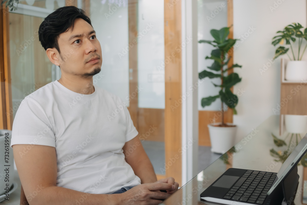 Asian man sitting and thinking something while working on computer at cafe, thoughtless, have no idea, freelance concept.
