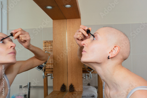 Woman with chemotherapy side effect apply mascara in mirror