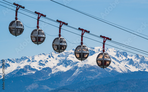 Gondola bubbles against the blue sky and the French Alps in the background. Cable car taking tourists to Fort de La Bastille in Grenoble, France photo