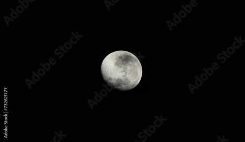 Bright full moon illuminating the nighttime sky against a black background
