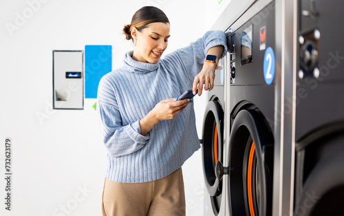 Schilderij op canvas A pretty girl stands inside a self-service laundry