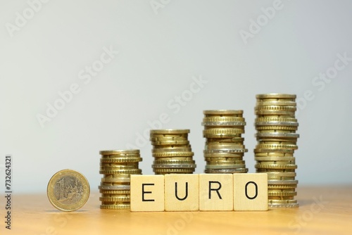 Steigender Eurokurs symbolisiert durch eine Euro Geldmünze, Stapel aus Münzgeld und den Schriftzug Euro, die Währung Euro gewinnt an Wert durch finanziellen Aufschwung, steigendes Gehalt und mehr Geld photo