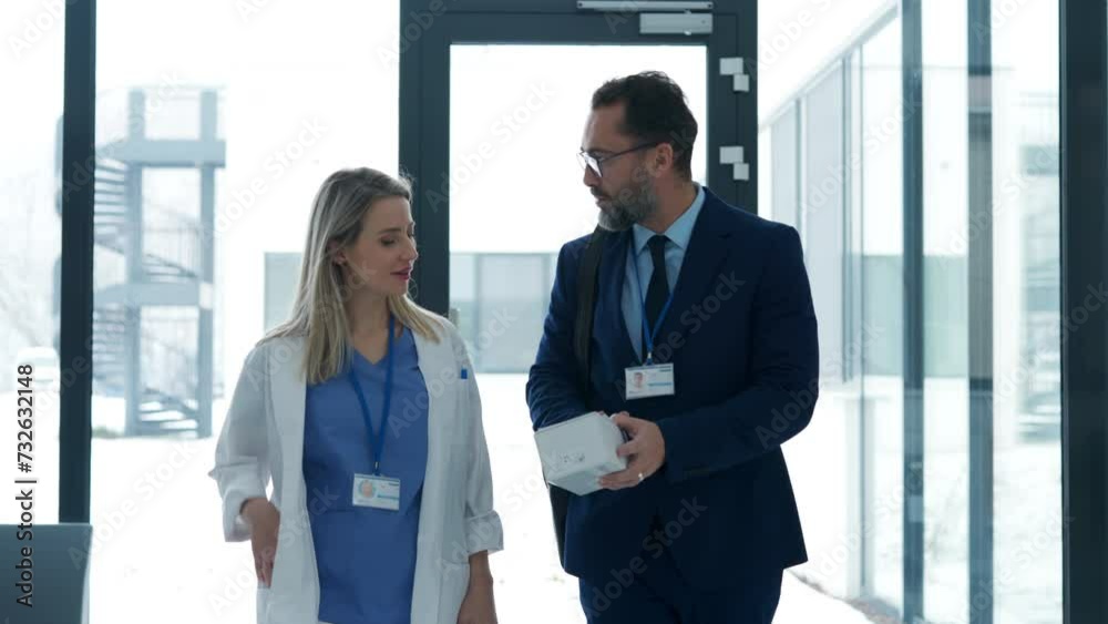 Pharmaceutical sales representative talking with doctor in medical building. Ambitious male sales representative presenting new medication. Pharmaceutical sales representative talking with doctor in medical building. Ambitious male sales representative presenting new medication.