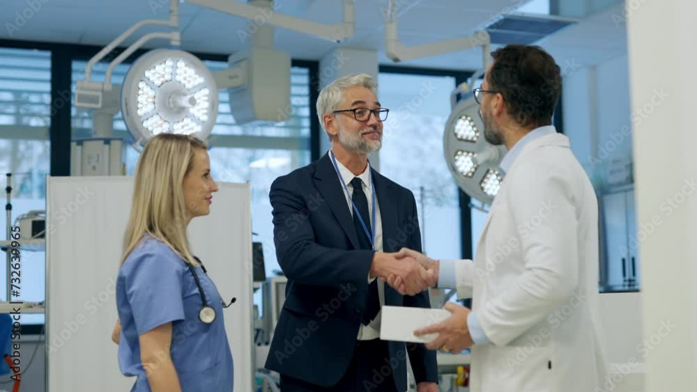Pharmaceutical sales representative presenting new medication to doctors in medical building, shaking hands. Through door. Pharmaceutical sales representative presenting new medication to doctors in medical building, shaking hands. Through door.