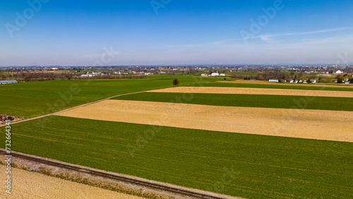 Vast Agricultural Fields With Distinctive Green And Beige Patterns Bordering A Small Town Under The Expansive Blue Sky.