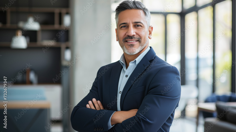 Fototapeta premium A cheerful man in a suit and tie stands confidently in an office environment, exuding professionalism and happiness.