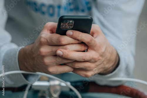 close-up of hands using mobile phone or smartphone on vintage bicycle
