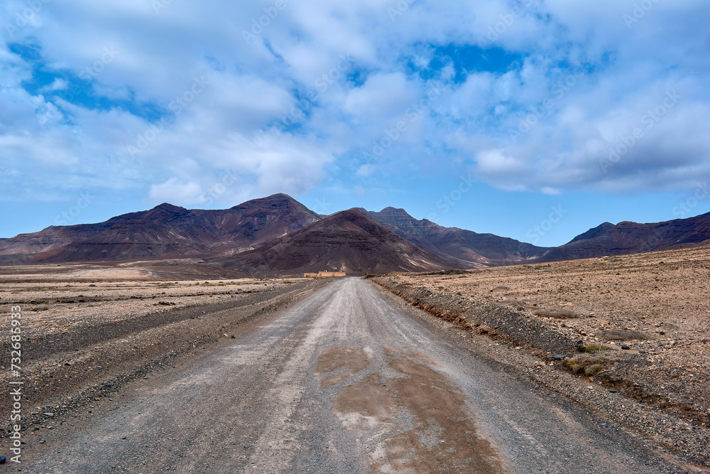 The road among volcanoes with arid terrain and volcanic rocks in Fuerteventura, Spain