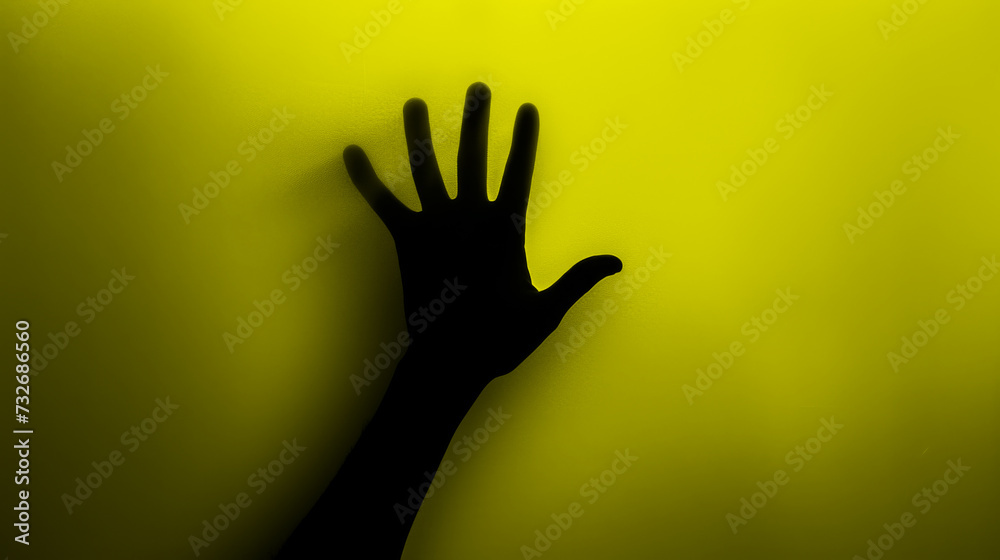 Hand silhouette on yellow background. Blurred human hand shape out of focus