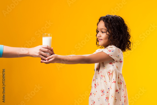 Smiling child girl taking fron hands glass of milk. Nutrition and health concept photo