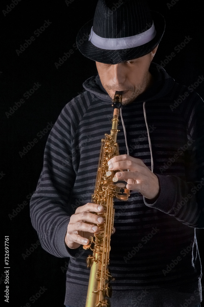 Naklejka premium soprano saxophone in the hands of a guy on a black background