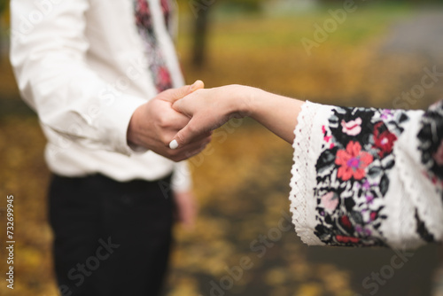 the bride and groom are holding hands with a bouquet of flowers and in traditional Ukrainian clothes