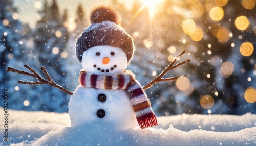 winter holiday christmas background banner closeup of cute funny laughing snowman with wool hat and scarf on snowy snow snowscape with bokeh lights illuminated by the sun © Alexander