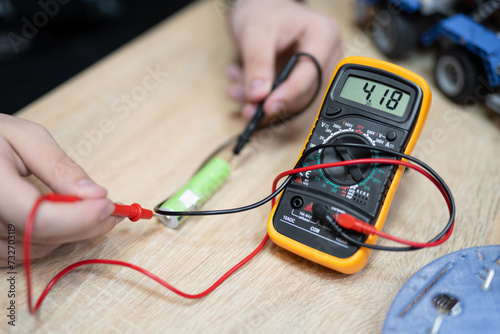 the engineer measures the voltage on the battery with a multimeter