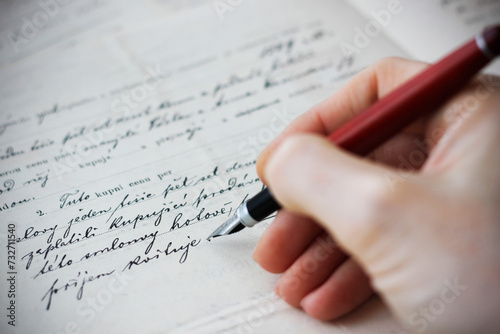 Close-up of a Caucasian female hand holding a fountain pen and writing a purchase contract in Czech language. Concept for old law, legal issues and old handwritten documents. photo
