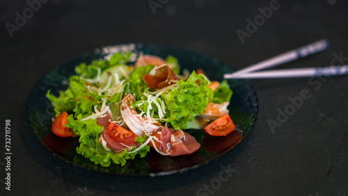 Seafood salad served on a beautiful plate. Salad with king prawns and prosciutto.