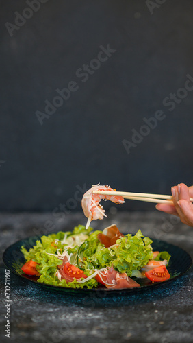 Seafood salad served on a beautiful plate. Salad with king prawns and prosciutto.