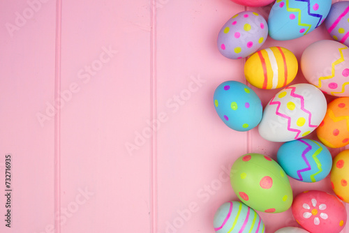 Colorful Easter Egg side border over a soft pink wood background. Copy space.