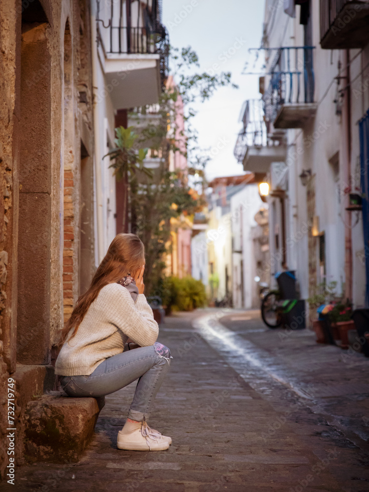 A young woman sitting on the street in the acient town of Lipari Island in Italy, Europe.
