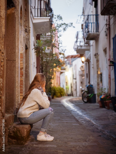 A young woman sitting on the street in the acient town of Lipari Island in Italy, Europe. © Milan