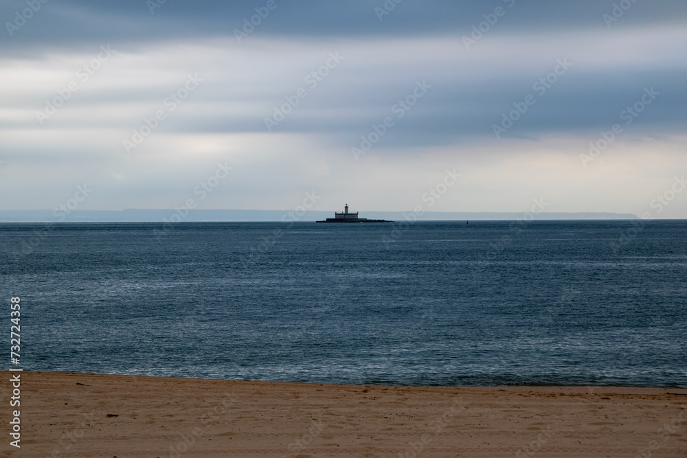 Seascape with a lighthouse in the middle of the sea and cloudy sky Seascape with a lighthouse in the middle of the sea and cloudy sky