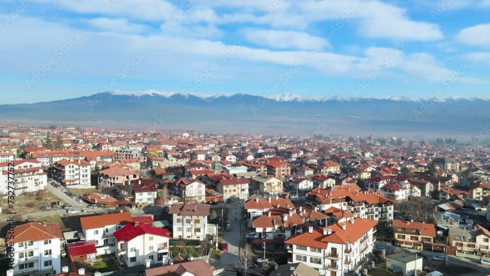 Aerial shot, flying low over buildings in Bulgarian resort Bansko towards distant Rila Mountains covered in snow. Aerial shot, flying low over buildings in Bulgarian resort Bansko towards distant Rila Mountains covered in snow.