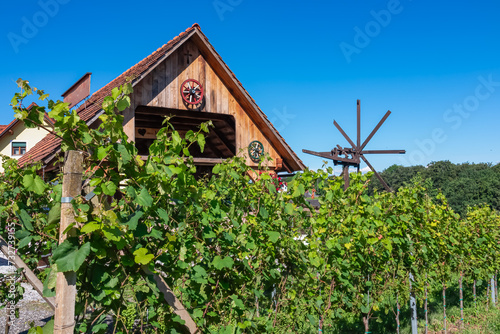 Scenic view of vineyards near Ehrenhausen an der Weinstrasse, Leibnitz, South Styria, Austria. Windmill klapotetz on winery Skoff stretching on green hills. Idyllic hiking trails in Styrian Tuscany photo