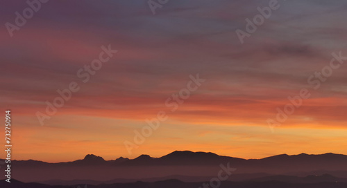 Il cielo rosso di nuvole sopra le montagne al tramonto © GjGj