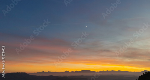 Tramonto cobalto e arancio con luna nel cielo sopra le valli e le montagne © GjGj
