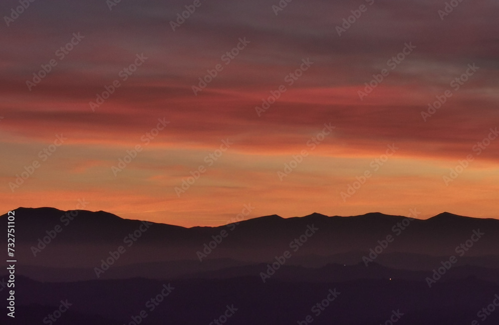 Il cielo rosso di nuvole sopra le montagne al tramonto