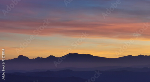 Tramonto blu e arancio con luna nel cielo sopra le valli e le montagne © GjGj