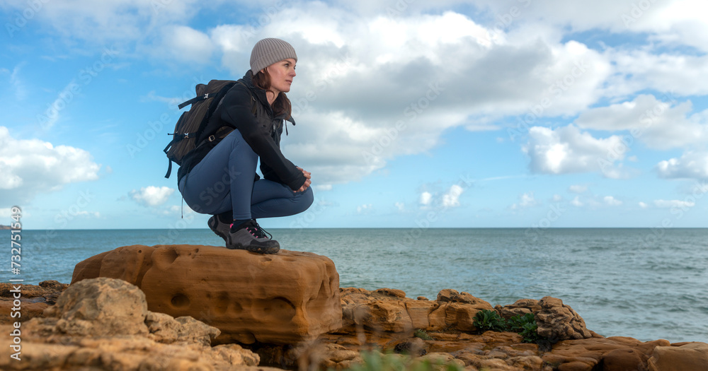 Sporty woman hiker on rocks by the sea Sporty woman hiker on rocks by the sea