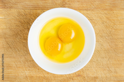 Raw eggs in bowl on the wooden table background. Studio photo. Shot from above. 