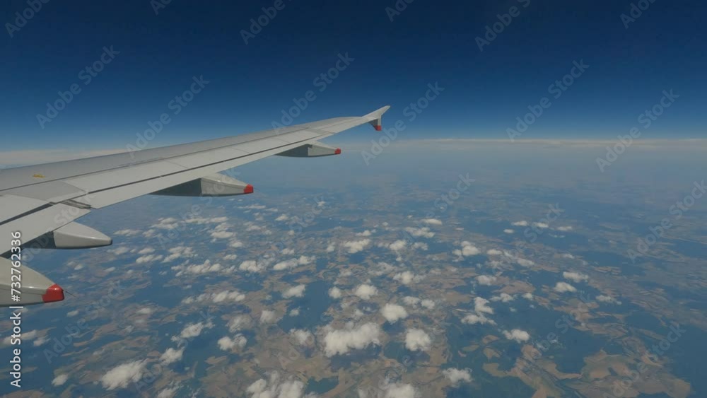 POV: A picturesque view from the window high above Germany while flying by plane. Beautiful views of fluffy clouds and landscape far below during flight with airplane over Europe to distant places.